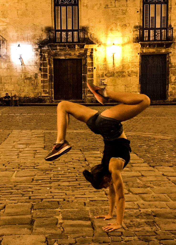 Girl doing a stag handstand in Old Havana, Cuba at night
