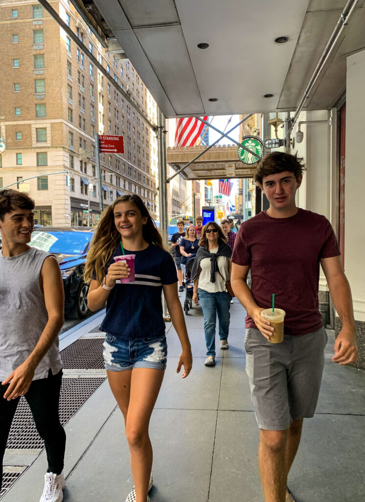 three teens walking the streets of New York City with Starbucks